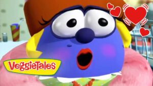Blue VeggieTales character with a surprised expression, blush on cheeks, logo 'VeggieTales' bottom left, and hearts in the corner.