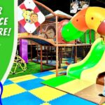 Cowboy-themed indoor play area with a man in cowboy gear beside a bright slide and colorful safety mats; text reads 'Indoor Playplace Adventure'.