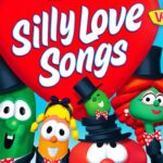 Colorful VeggieTales characters in tuxedos gathered around a large red heart with the words “Silly Love Songs” and a VeggieTales logo in the corner, bright blue background.