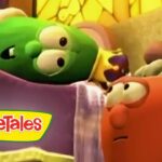 Two VeggieTales characters in a bed scene: a green vegetable lying under a blanket and a red-orange character looking at it as if talking, with a VeggieTales logo visible on the blanket.