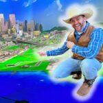 Cowboy in a blue plaid shirt points at a glowing 3D city map with green land and blue water, smiling at the scene.