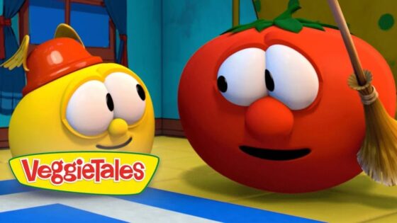 Animated VeggieTales scene: a yellow round character wearing a small red firefighter helmet chats with a red tomato character holding a broom indoors, VeggieTales logo visible.