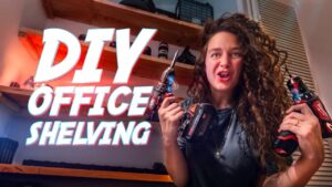 Woman in a workshop holding two cordless drills with bold 'DIY Office Shelving' text overlay on the screen, promoting a DIY tutorial