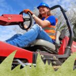 Smiling worker in a blue hard hat and orange safety vest driving a red ride-on lawn mower outdoors.