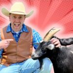 Man in a cowboy hat and brown vest crouches beside a black and white goat, pointing and smiling against a red comic-book style background.