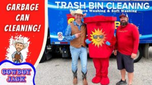 Promo photo for garbage can cleaning service with two men in western outfits posing with a red sun-logo trash can mascot in front of a blue Trash Bin Cleaning truck, promoting the service.