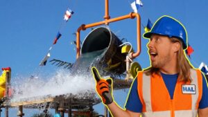 Construction worker in an orange safety vest and blue helmet points at a water splash from a slide or pipe structure behind him.