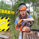 Man in safety gear with a running chainsaw cutting a log in a forest setting, surprised expression on his face.