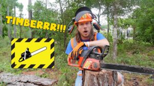 Man in safety gear with a running chainsaw cutting a log in a forest setting, surprised expression on his face.