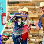 Cowboy couple in hats blowing bubbles at a wand, with a turquoise panel reading 'All Kinds of Bubbles!' and a 'Cowboy Jack' logo on the left.