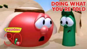 Red tomato and green bean VeggieTales characters in a desert scene, with bold 'Doing What You're Told' text in the corner and a 30th anniversary logo nearby, conveying a moment of concern or surprise.