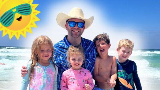 A smiling man in a cowboy hat and blue shirt with four kids on a sunny beach, waves in the background and a cartoon sun in the corner.