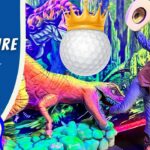 Man in a cowboy vest and hat poses with a neon dinosaur in a colorful putt-putt adventure scene; a crowned golf ball hovers above.