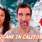 Two people look surprised in front of a satellite image of a hurricane near California, with a red arrow pointing to the storm.