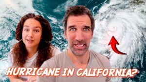 Two people look surprised in front of a satellite image of a hurricane near California, with a red arrow pointing to the storm.