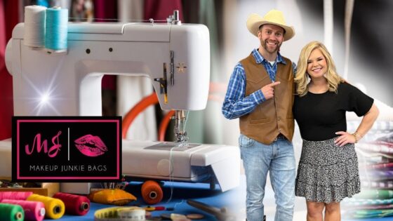 Sewing machine on a blue-worktable with colorful thread spools and fabric; logo reads 'Makeup Junkie Bags' as two hosts stand nearby, smiling.