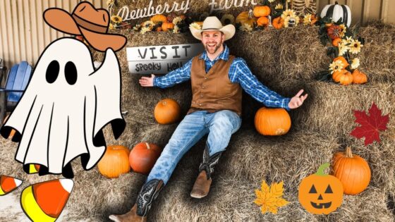 Smiling man in a cowboy outfit sits on hay bales with pumpkins and autumn decor around him, Halloween vibe.