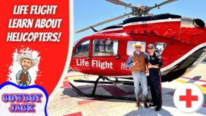 Two men in cowboy outfits pose beside a bright red Life Flight helicopter on a sunny tarmac behind the scene banner. The left shows a bold 'Life Flight Learn About Helicopters!' graphic.