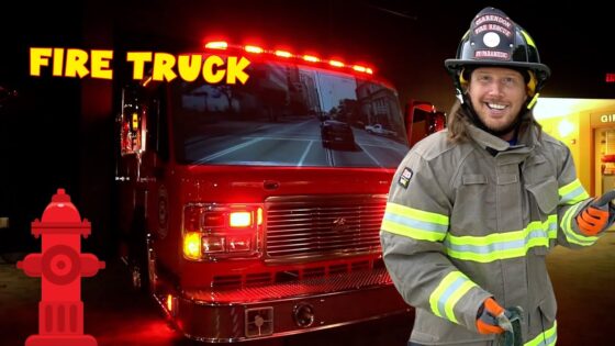 Smiling firefighter in turnout gear with a red fire truck inside a station and bold 'FIRE TRUCK' text in yellow above.