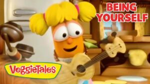 Orange VeggieTales character with yellow pigtails plays a guitar in a cozy kitchen scene; VeggieTales logo visible and 'Being Yourself' text top right.