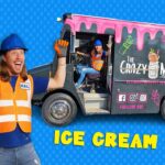 Man in orange safety vest and blue hard hat holds a huge toy ice cream cone, excited pose, against a blue dotted backdrop.