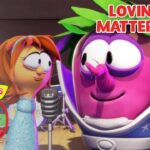 Pink VeggieTales character sings into a microphone while other colorful veggie characters look on on a stage; banner reads 'Loving, no matter what'.
