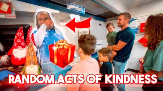 Family of four in line at a store counter looks at a life-size cutout of a man, with a red gift box and Christmas decorations nearby; bold 'RANDOM ACTS OF KINDNESS' caption visible.
