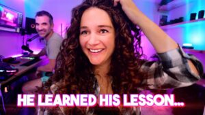 Cheerful woman with curly hair in foreground adjusting her hair, man at a computer desk in a neon-lit room; text overlay reads 'HE LEARNED HIS LESSON...'