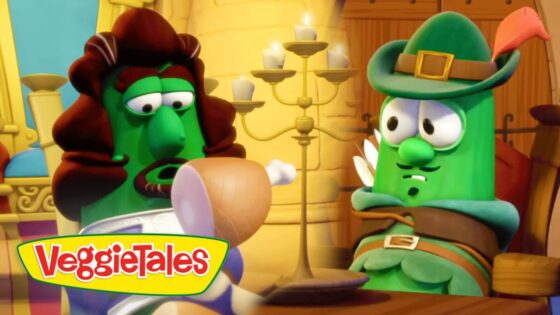 Two green VeggieTales characters sit at a wooden table in a bright castle room; one with a brown wig, the other wearing a green hat with a feather, logo visible in corner.