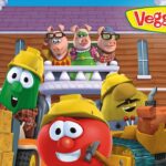 VeggieTales characters in hard hats at a construction site in front of a wooden house, tomato in front smiling with a hammer nearby.