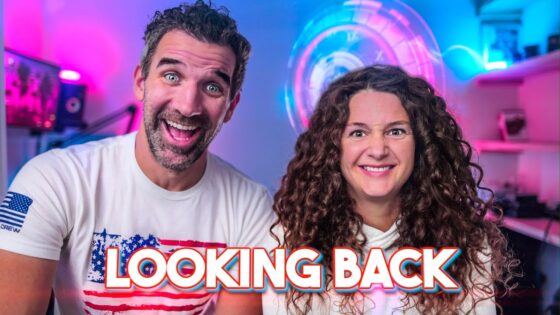Smiling man and woman in a colorful tech-themed room with neon lights; bold 'LOOKING BACK' text overlays the bottom edge.