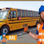 Man in blue hard hat and orange safety vest stands beside a yellow school bus in a parking lot, giving a thumbs-up gesture.