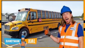Man in blue hard hat and orange safety vest stands beside a yellow school bus in a parking lot, giving a thumbs-up gesture.