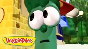 Green VeggieTales character with oversized eyes wearing a Santa hat, against a yellow brick backdrop.