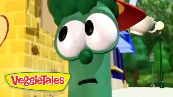 Green VeggieTales character with oversized eyes wearing a Santa hat, against a yellow brick backdrop.