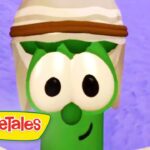 Larry the Cucumber from VeggieTales, wearing a white hat with a brown band, against a purple background.