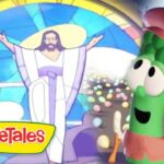 Green veggie character wearing a brown hat smiles at Jesus with open arms in a bright stained-glass VeggieTales scene.