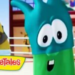 Animated VeggieTales scene: a teal cartoon vegetable with big eyes in a ring, foreground, with a yellow-bearded character in the background and the VeggieTales logo bottom left.