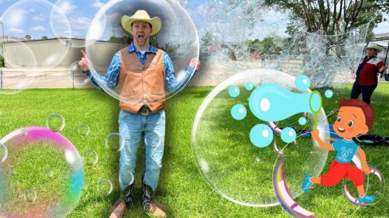 Man in a cowboy hat and vest poses on a grassy field, surrounded by giant bubbles and a cartoon boy drawing bubbles on the right side.
