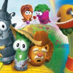Group of VeggieTales characters posing on a sunny grassy hill, smiling at the camera.