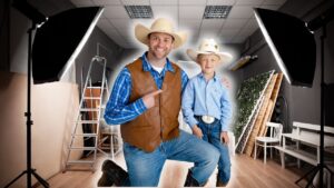 Man and boy in cowboy outfits posing in a photography studio with lights and props nearby.