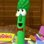 Green cucumber character from VeggieTales with a red bow tie, smiling in a colorful block-filled scene (logo bottom-left).