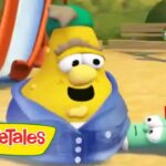 Yellow VeggieTales character wearing a blue hoodie sits on a sandy playground with a slide in the background and small green friends nearby, VeggieTales logo visible on the bottom left.
