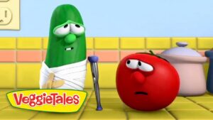 Green cucumber with a white bandage and crutch speaks to a worried red tomato in a bright yellow kitchen, VeggieTales scene.