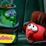 Green cucumber wearing a hat talks to a red rounded veggie in a cave; VeggieTales logo visible at bottom left.