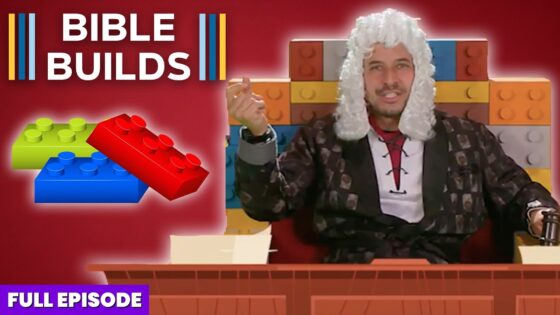 Host wearing a white powdered wig sits at a wooden desk in front of a colorful Lego brick backdrop; thumbnail for a video titled 'Bible Builds'