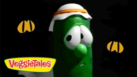 Green VeggieTales cucumber character with a white and orange headband on a black background, VeggieTales logo in the bottom-left corner.