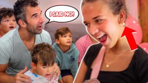 A man and two kids sit on a couch looking toward a laughing woman at right; a speech bubble says 'I SAID NO!' indicating a playful moment at a party.