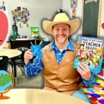 Man in a cowboy hat and vest sits in a colorful classroom, holding a 'How To Get Your Teacher Ready' book and a blue cup. (Back to School theme)