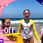 Thumbnail for a video: three kids on a sunny beach with surfboards, overlaid with 'Life of Riley' and 'Surf Off' text and an 'Exclusive' badge.